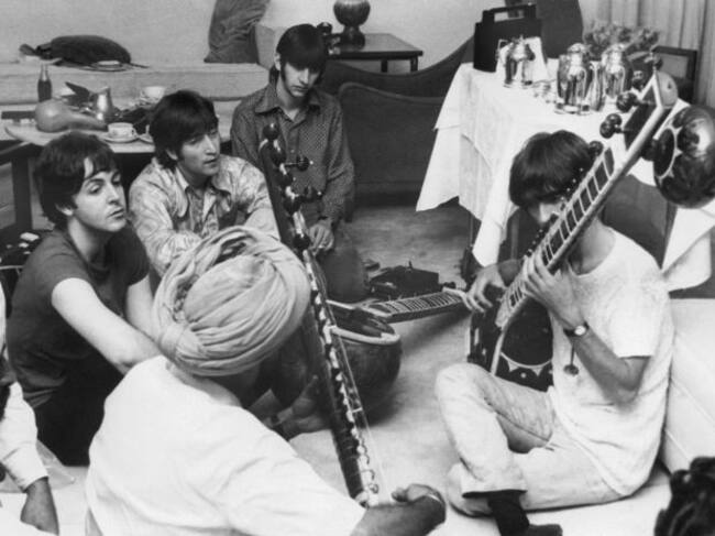 George Harrison recibe instrucciones de cómo tocar el sitar, mientras el resto de la banda observa.